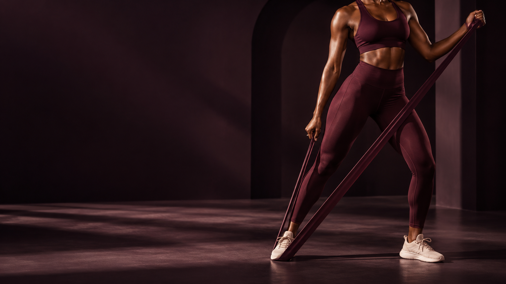 Woman exercising with a resistance band in a dark studio